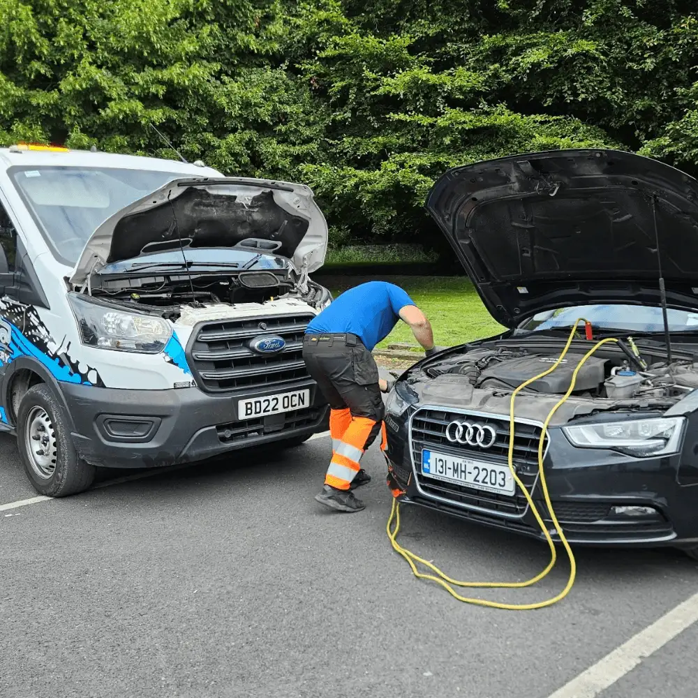 JC Recovery operator providing a mobile battery jump start to a car in a Dublin park.